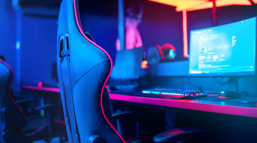 Blurred background computer pc, keyboard armchair, blue and red lights. Concept online eSports arena for gamer playing tournaments.