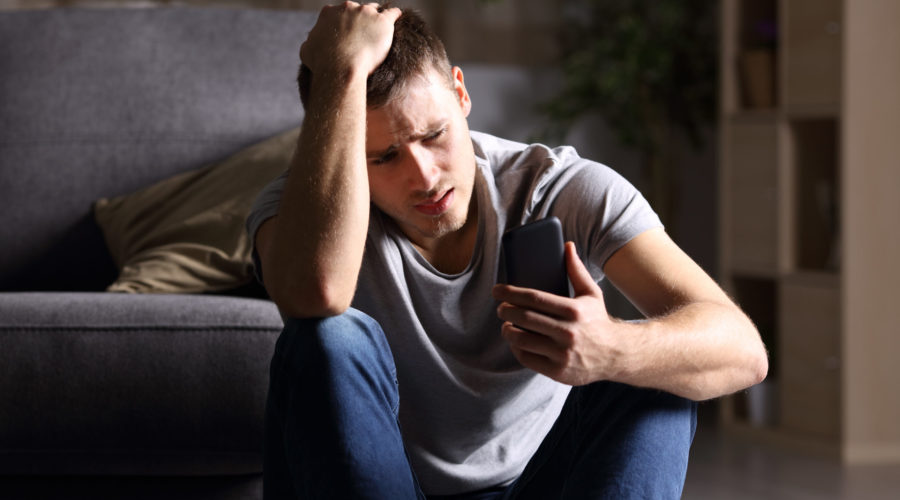 Single sad man checking mobile phone