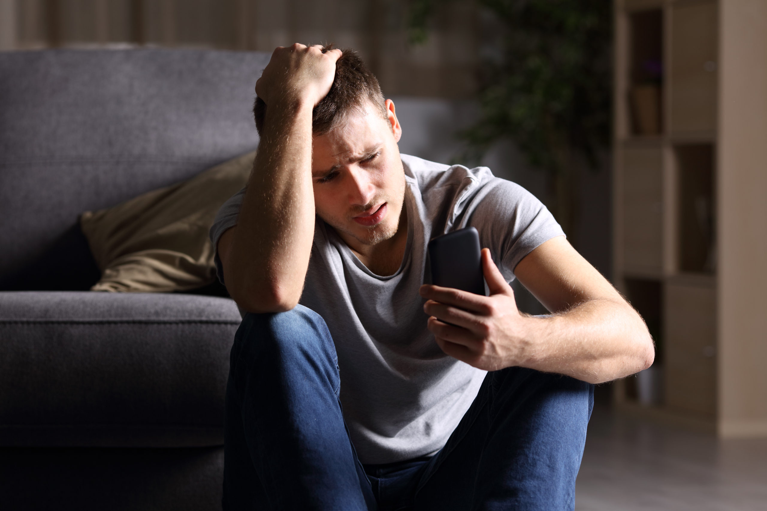 Single sad man checking mobile phone reading What Hacking Means and Data Security Laws