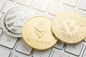 cryptocurrency coins - Litecoin, Bitcoin, Ethereum sitting on keyboard